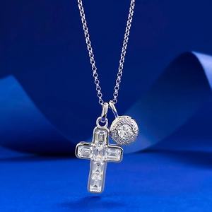 S925 sterling silver cross necklace with baguette crystals on a dark blue silk background