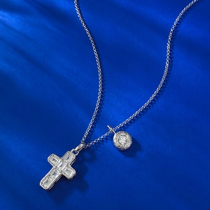 S925 sterling silver cross and round medallion layered necklace on royal blue surface