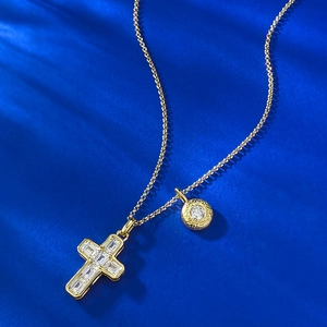 Gold cross pendant necklace with baguette zircons on a navy blue background