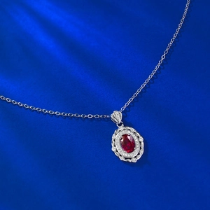 Gros plan d'un pendentif ovale avec gemme rouge en argent S925 et halo de diamants