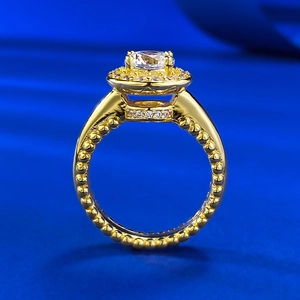 Bague halo dorée élégante avec pierre centrale sur fond en satin bleu foncé soyeux