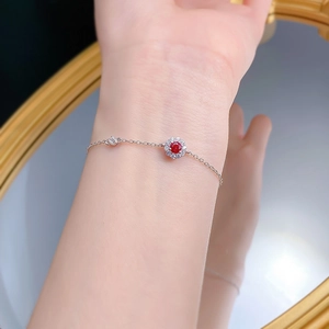 Detail of S925 silver bracelet with red ruby flower and delicate star charm on wrist