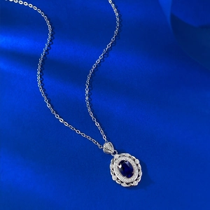 Macro d'un pendentif ovale avec pierre bleue serti de diamants sur monture en argent ciselé