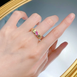 Detailed view of hand-hammered gold ring with a pear-cut pink gemstone on a finger