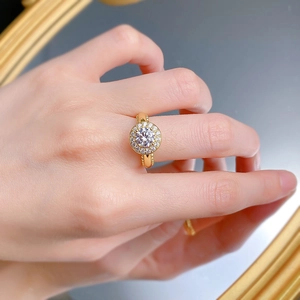 Gros plan d'une bague en argent S925 doré avec sertissage halo en diamant rond sur le doigt