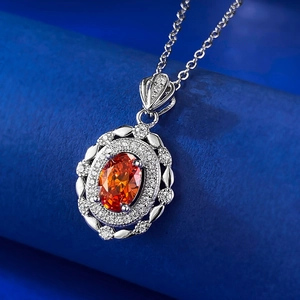 Détail macro du pendentif en pierre orange ovale avec halo de diamants et monture argent