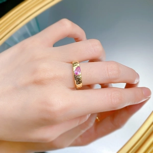 Detail of gold hammered ring with pear-cut pink gemstone on hand with reflection