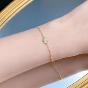 Dettaglio di un bracciale a goccia d'oro con intarsio di zirconi sul polso femminile
