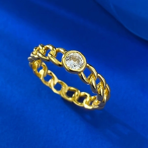 Gold Cuban link chain ring with a brilliant round center stone on blue velvet