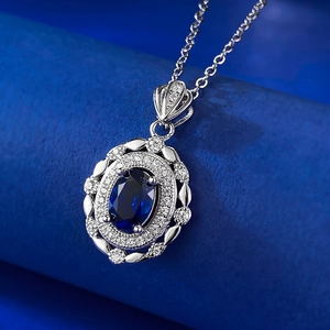 Détail macro du pendentif saphir bleu ovale avec halo de diamants sur chaîne argentée