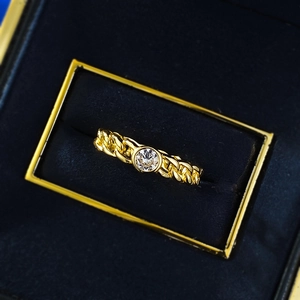 Detail of a golden Cuban link chain ring with a sparkling round zircon in a velvet box