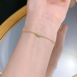 Dettaglio ravvicinato di un delicato bracciale in argento S925 dorato con ciondolo a goccia
