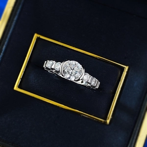 Macro shot of a 7mm round cut solitaire ring with side stones in a blue jewelry box
