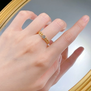 Detail of a gold-plated chain link ring with a clear round cubic zirconia on finger