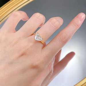 Close-up of heart-shaped 10x8mm high-carbon diamond ring on hand in golden finish