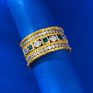 Detailed macro shot of vintage gold-plated wide band ring with square green crystals