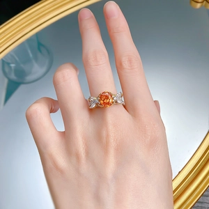 Detail of S925 silver ring with oval orange gemstone and diamond bow setting