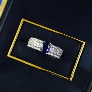 Détail d'une bague saphir bleu ovale avec pavé de diamants dans son écrin en velours