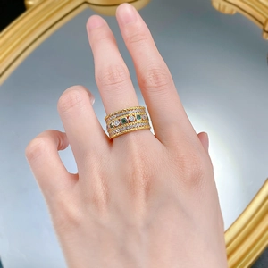 Close-up of S925 silver gold ring with square green diamonds and braided metal texture