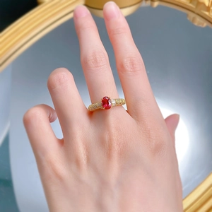 Détail macro d'une bague rubis ovale sertie de diamants en or 18 carats au doigt