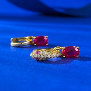 Macro shot of 18K gold snake earrings with pave zirconia and oval red gemstone drops