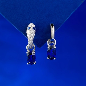 S925 silver earrings featuring a snake head design and oval blue gemstones on a blue stand