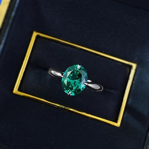 Detailed view of an oval emerald ring in a four-prong silver setting inside a gift box