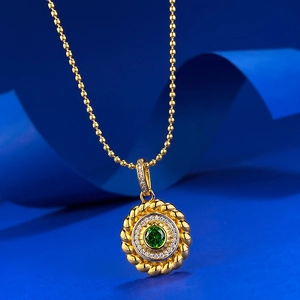 Macro shot of gold pendant with green gemstone and beaded chain on blue ribbon