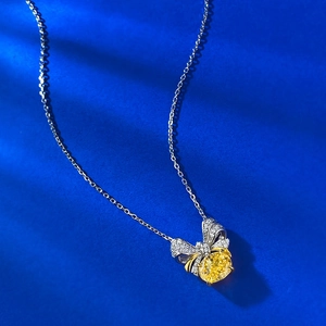 Gros plan du pendentif nœud en argent avec diamant jaune sur un fond bleu profond
