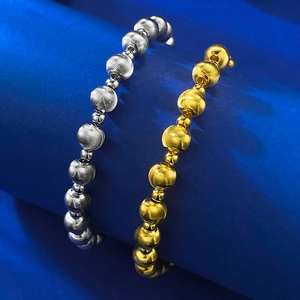 Macro shot of silver and gold beaded bracelets featuring radial brushed metal texture