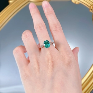 Macro detail of oval green emerald ring in silver claw setting on model's hand