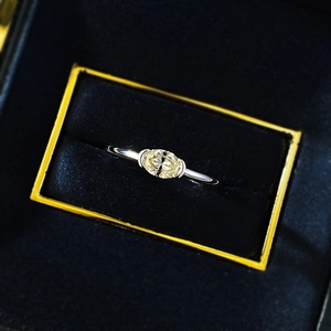 Macro shot of an oval yellow gemstone set in a minimalist polished silver ring