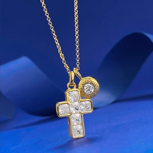 Detail of gold cross pendant necklace with square-cut gems on a blue silk background