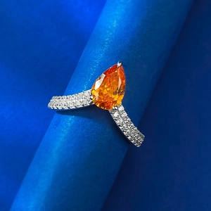 Macro d'une bague en argent 925 en V avec pierre orange poire et micro-pavage de diamants