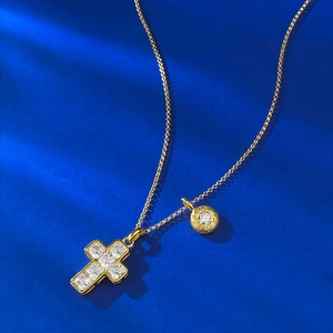 Detail of gold cross pendant necklace with square cubic zirconia on deep blue background