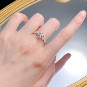 Gros plan d'une bague champagne de 1 ct avec des trèfles latéraux sur le doigt