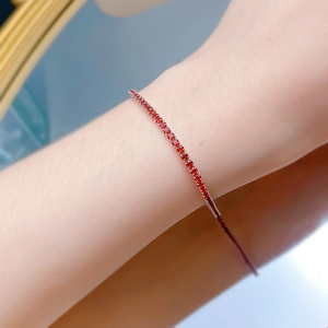 Detailed shot of an S925 silver tennis bracelet with round red zircons on a wrist
