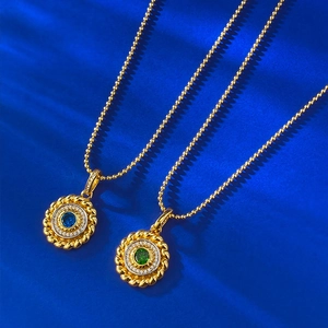 Detail of round gold pendant necklaces with blue and emerald green gemstones on blue background