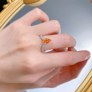 Détail d'une bague avec pierre orange en forme de poire et anneau en V argenté pavé