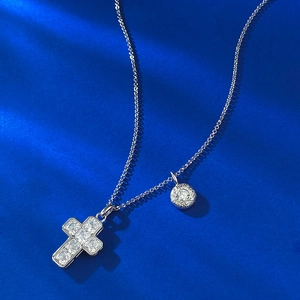 Macro shot of S925 silver cross pendant and round charm with sparkling pavé stones