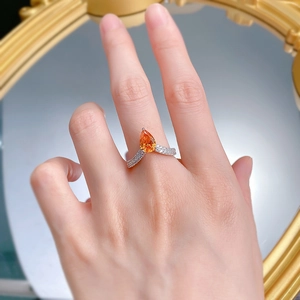 Gros plan d'une bague en argent 925 avec pierre orange poire et anneau pavé en forme de V