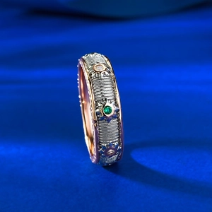 Macro view of two-tone ring featuring a green gemstone and brushed striped texture
