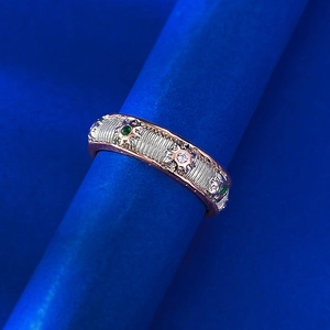 Macro view of bicolor gold ring with green emerald stone and sunburst brushed texture