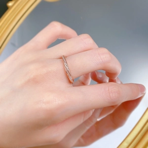 Detail of rose gold crisscross diamond ring on finger with elegant mirror reflection