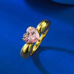 Bague avec pierre rose en forme de cœur, monture dorée et design sphérique moderne