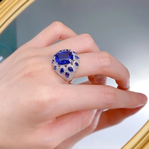 Detail of cushion-cut blue corundum ring with sparkling teardrop accents on hand