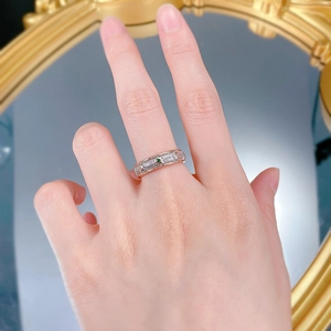 Detail of hand wearing a gold embossed ring with an emerald green gemstone