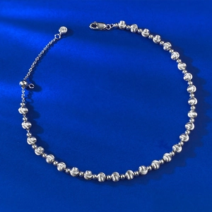 Detail of silver beaded bracelet with cat eye texture, lobster clasp and zircon drop