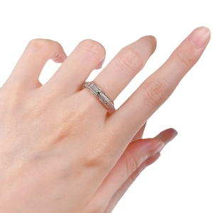 Two-tone brushed stripe ring with center green gemstone worn on model's middle finger