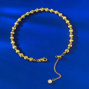 Detail of gold beaded bracelet with lobster clasp, adjustment chain and zircon pendant